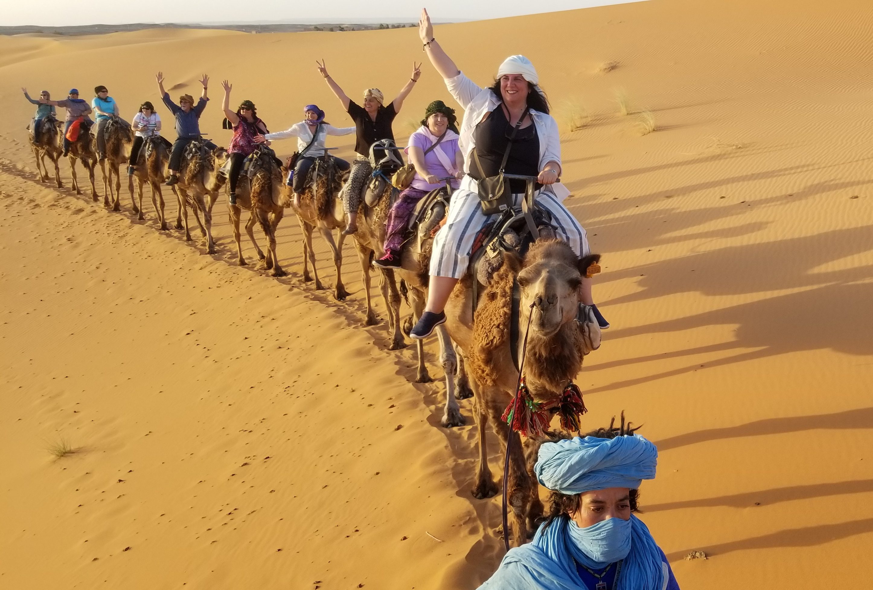 Camel train with travelers cheering