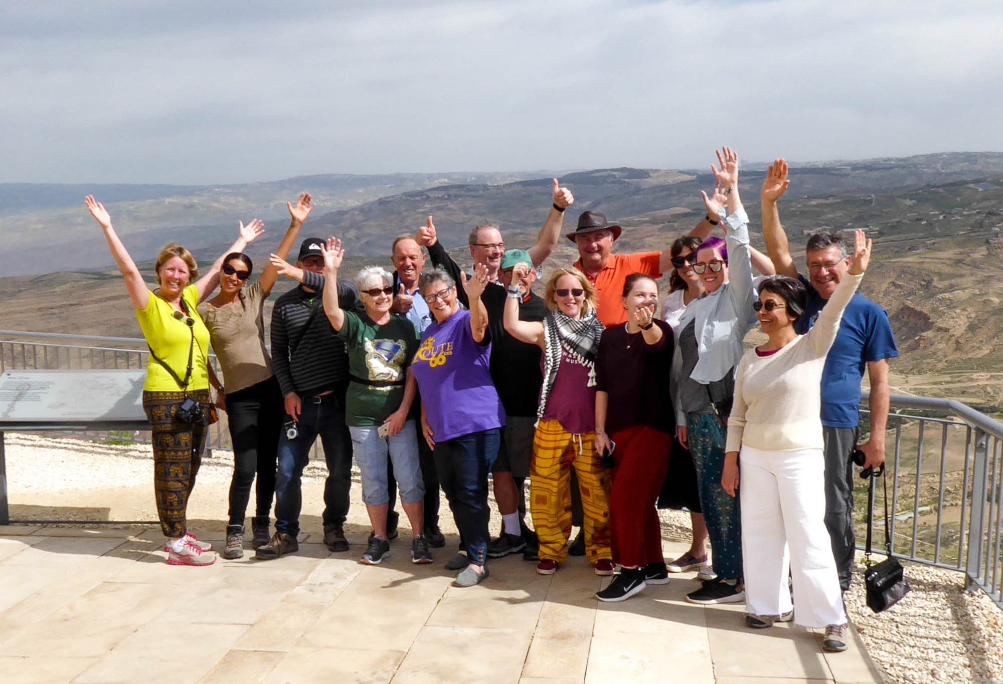 Tour group cheering in front of mountain landscape