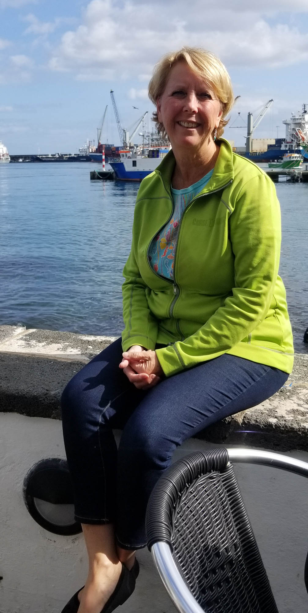 Woman sitting on wall in Sao Miguel, Azores harbor